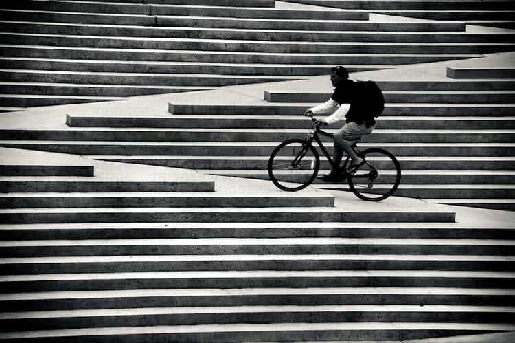 A man riding his bike up the stairs at Robson Square in Vancouver Canada.