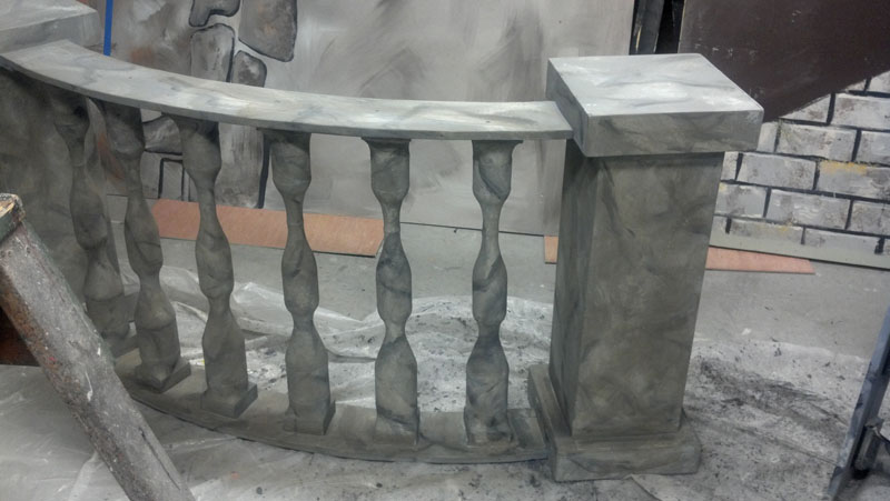 A curved balustrade railing unit in a scene shop.  It has marble texture in gray tones.