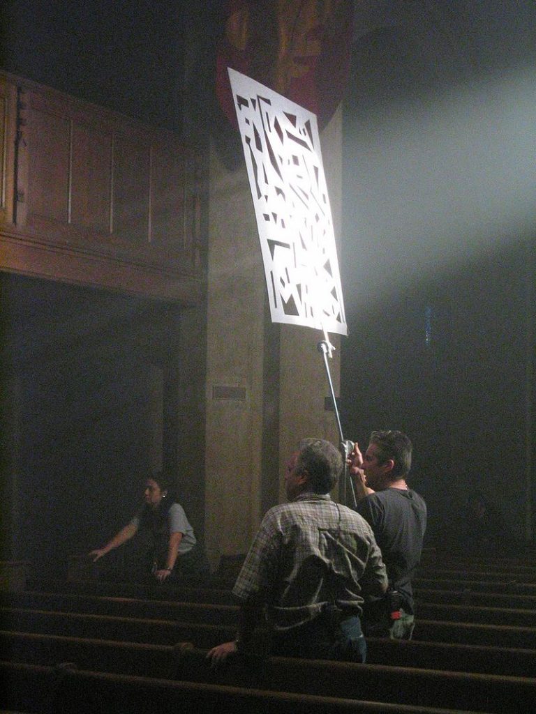 Crew members on National Treasure using a large cookie on a pole to cast textured light on the film set